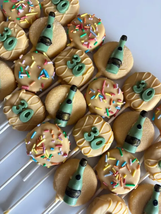 Gedipte koekjes met champagnefles-thema voor een verjaardag
