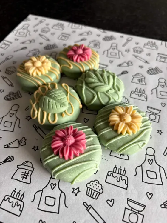 Groene gedipte koekjes met roze en gele bloemversiering