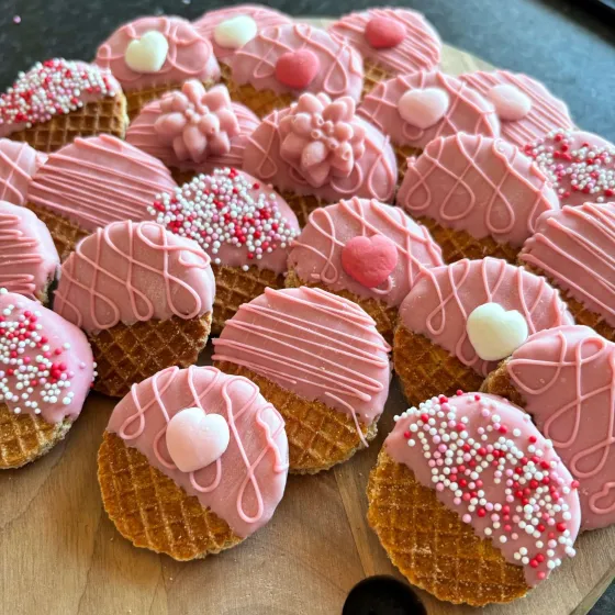 Roze gedipte mini-stroopwafels met hartjes en sprinkles